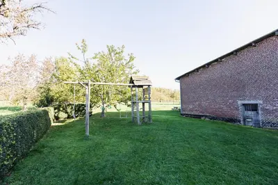 a playground in a yard next to a brick building at Domein Tombos in Gingelom