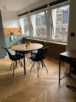 a table and chairs in a room with windows at L’émeraude in Liège