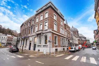 a large brick building on a city street with cars parked at The 99, Appartement sauna & parking in Liège