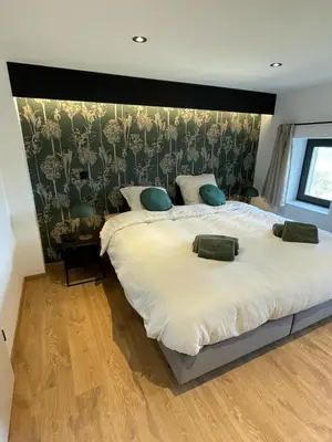 a bedroom with a large white bed with a wall at Gite de Clermont in Thimister