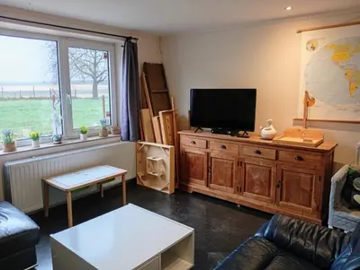 a living room with a flat screen tv on a wooden cabinet at Belevingshoeve 