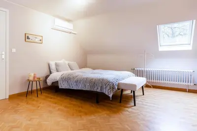 a white bedroom with a bed and a stool at Arthurs Palace in Heusden - Zolder