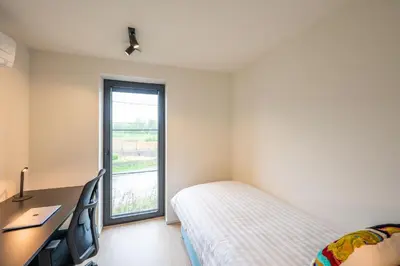 a bedroom with a bed and a desk and a window at unique hideaway, holiday house with large garden in Kortenaken