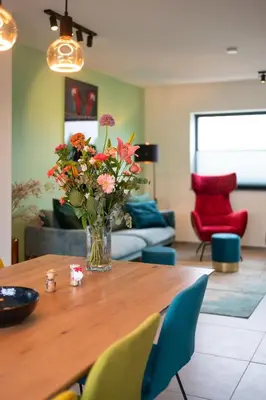 a vase of flowers on a wooden table in a living room at unique hideaway, holiday house with large garden in Kortenaken