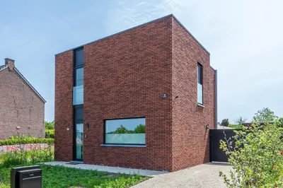 a red brick house with a large window at unique hideaway, holiday house with large garden in Kortenaken