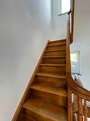 a wooden staircase in a house with a wooden chair at Agréable duplex proche de toutes commodités in Ans