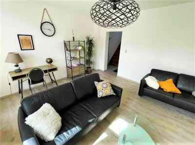 a living room with a black leather couch and a table at Agréable duplex proche de toutes commodités in Ans
